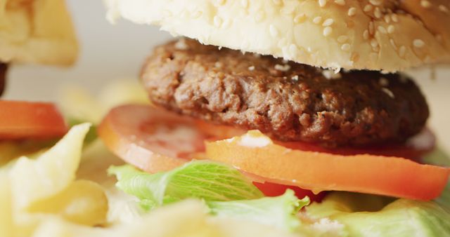 This image captures a close-up of a delicious cheeseburger featuring a juicy beef patty, fresh lettuce, and ripe tomato. Ideal for use in food blogs, restaurant menus, fast food advertising, and culinary articles.