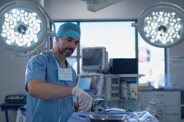 Male surgeon holding surgical instrument in operating room at hospital