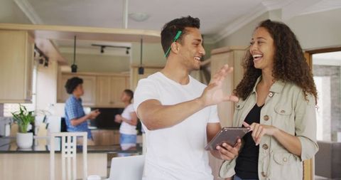 Young Friends Laughing with Tablet in Modern Kitchen