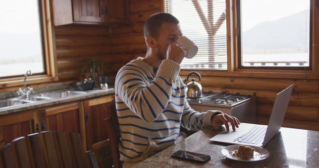 Man in Cozy Cabin Working on Laptop and Drinking Coffee - Download Free Stock Images Pikwizard.com