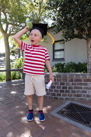 Young boy celebrating elementary graduation wearing mortarboard holding diploma
