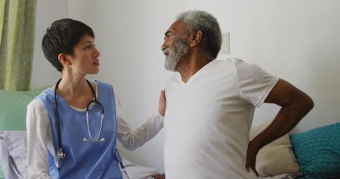 Senior Man with Back Pain Consulting Doctor at Retirement Home