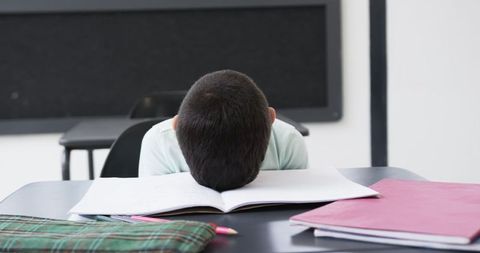 Young Student Falling Asleep on Desk During Classroom Study Session