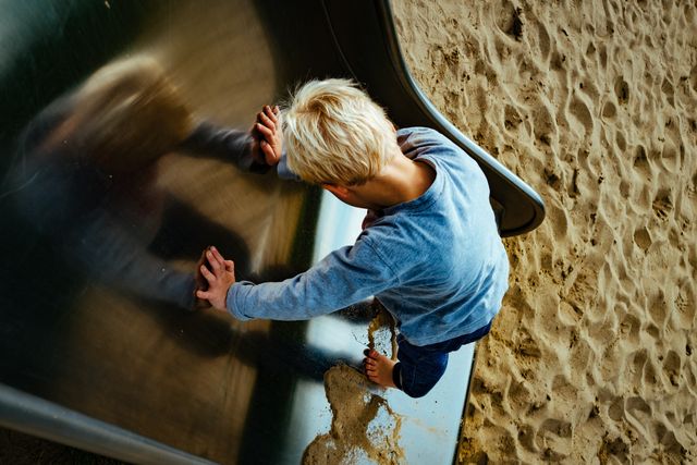 Blonde child climbing slide barefoot in sandy playground - Download Free Stock Images Pikwizard.com
