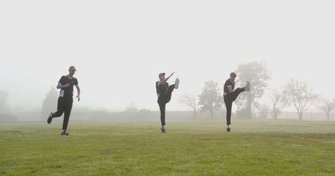 Male Athletes Practicing High Kicks On Misty Morning