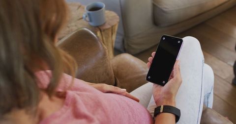 Pregnant woman at home using smartphone