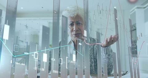 Senior Woman Reviewing Market Charts Using Virtual Finance Dashboard in Kitchen