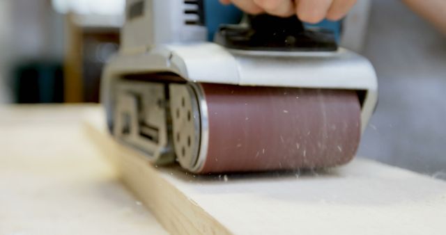 Shows detailed view of electric sander smoothing wooden surface, highlighting the precision and workmanship involved. Ideal for illustrating DIY projects, carpentry tutorials, woodworking tools, home improvement projects, or craftsmanship blogs.