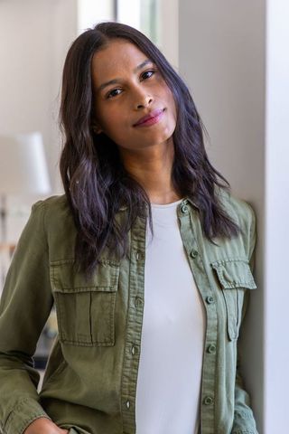 Confident young woman leaning by window in olive shirt, approachable professional portrait