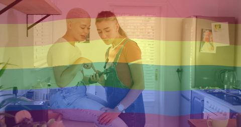 Diverse Female Couple with Rainbow Overlay Using Smartphone