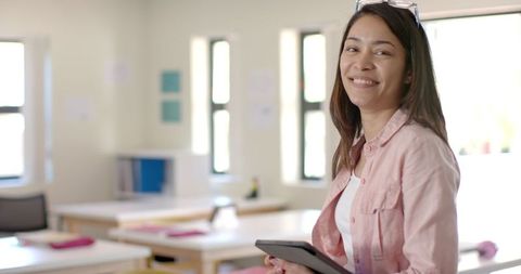 Confident Teacher Holding Tablet in Classroom Setting