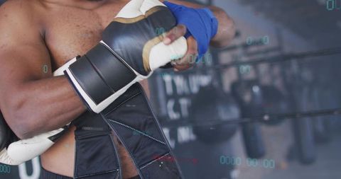 Boxer wrapping hands and holding glove over shoulder preparing for training session