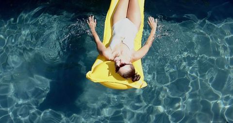 Teen girl relaxing on float in sparkling pool water