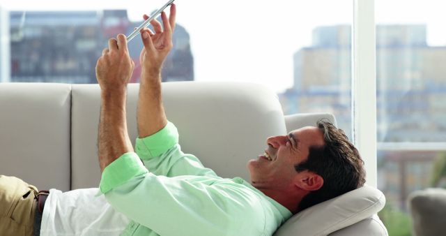 Man Relaxing on Sofa Using Smartphone in Bright Modern Living Room - Download Free Stock Images Pikwizard.com