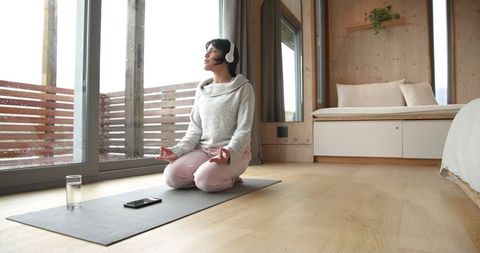 Woman Meditating with Headphones in Cozy Cabin Bedroom