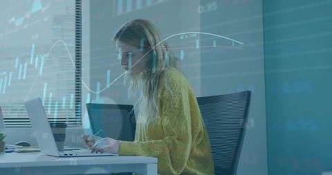 Young analyst wearing yellow sweater analyzing stock charts on laptop and smartphone