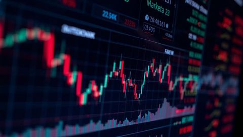 Displaying candlestick chart tracking market volatility with volume histogram and tickers