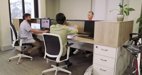 Modern office team discussing project strategy at shared workstation