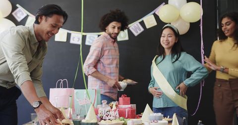 Diverse team celebrating baby shower office party together