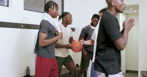 Locker room teammates holding basketball preparing laughing after practice