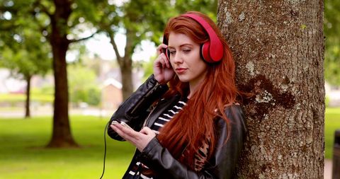 Redhead Woman Enjoying Music with Headphones Outdoors