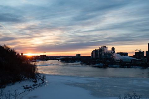 Breathtaking Winter Sunrise over City Skyline by Frozen River