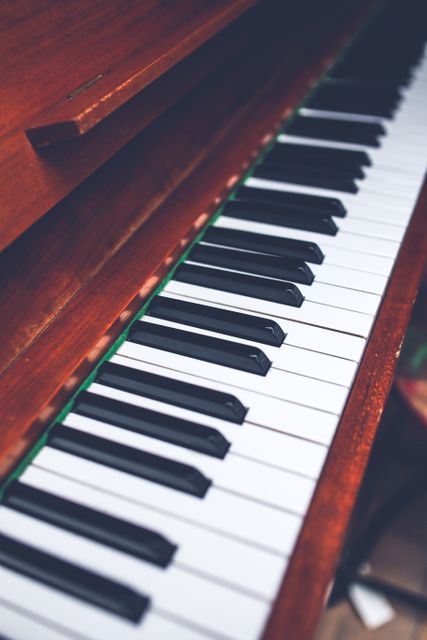 Showing detailed shot of piano keys focusing on craftsmanship and texture of a well-maintained antique wooden piano. Perfect for use in articles about music history, vintage instruments, learning piano, and classic music décor.