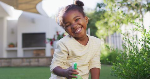 Joyful Girl Watering Plants Outdoors in Sunny Garden - Download Free Stock Images Pikwizard.com