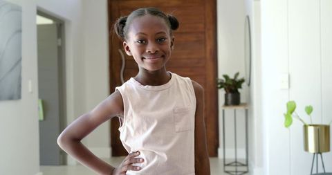 Confident young african girl posing with hand on hip in bright modern entryway