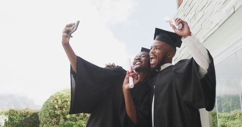 African American Graduates Celebrating with Selfie Outdoors