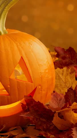 Vertical jack-o'-lantern moving over autumn leaves with warm flickering candlelight