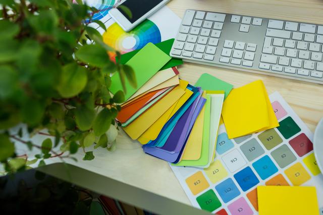 This image shows a vibrant and organized workspace with colorful parcel tags and sticky notes spread out on a desk alongside a keyboard. Ideal for illustrating concepts related to office organization, creative workspaces, productivity, and design. Perfect for use in articles, blogs, and marketing materials about office supplies, workplace efficiency, and creative environments.