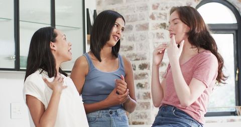 Excited multiracial friends celebrating engagement in kitchen