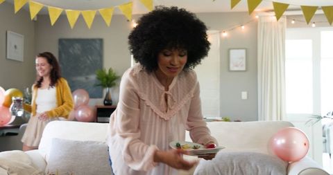 Women Preparing Decorated Living Room for Celebration Gathering