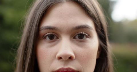 Closeup portrait young woman gazing with clear skin and natural makeup outdoors