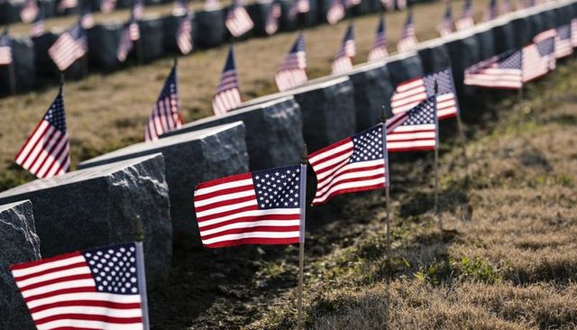 Fluttering american flags lining cemetery rows of granite headstones memorial tribute