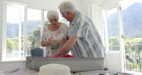 Senior Couple Packing Suitcase for Vacation in Bedroom