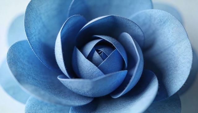 Blue fabric rose macro showing spiral petals and woven textile texture