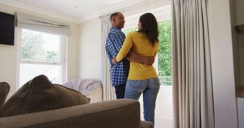 Couple embracing by window in bright living room