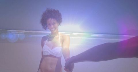 Woman in White Bikini Holding Hands at Sunny Beach with Lens Flare