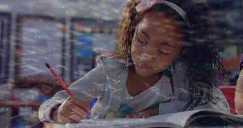Young student writing in notebook while focusing on classroom work and studying attentively