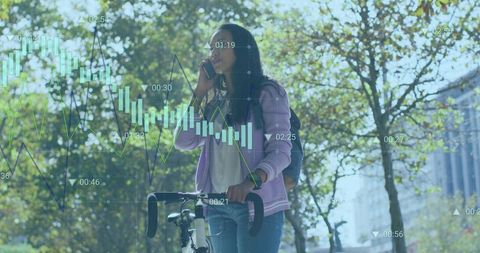 Young woman talking on phone beside bicycle on tree-lined urban street with data graphs overlay