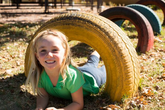 Portrait of happy girl playing with tire at playground