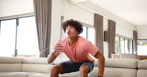 Excited Young Man Watching TV with Popcorn at Home - Download Free Stock Images Pikwizard.com