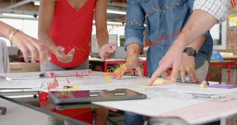 Design team collaborating over blueprints and tablet with analytics overlays