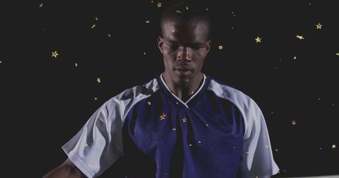 Stoic male athlete standing wearing navy sports jersey surrounded by gold star confetti