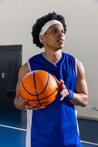 African American Basketball Player Holding Ball in Gym Environment