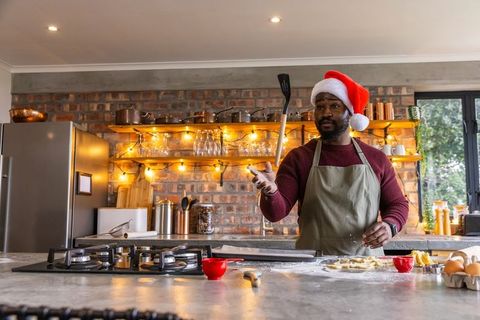 Baking holiday cookies wearing santa hat in cozy rustic brick kitchen