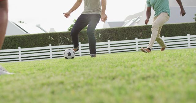 Adults are engaged in a friendly soccer game on a well-manicured green lawn in a quiet neighborhood. This image can be used to promote outdoor activities, community engagement, and fitness. Useful for blog posts about leisure time, healthy lifestyles, or community get-togethers.