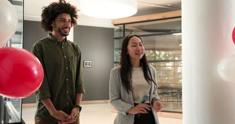 Diverse professionals celebrating office opening amidst balloons